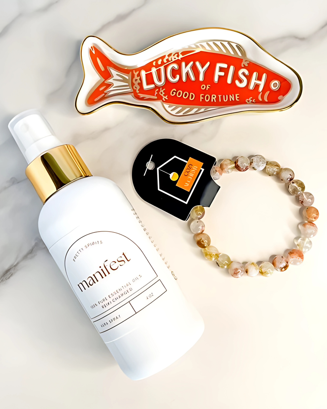 Skincare product, Lucky Fish ornament, and bracelet on a light background