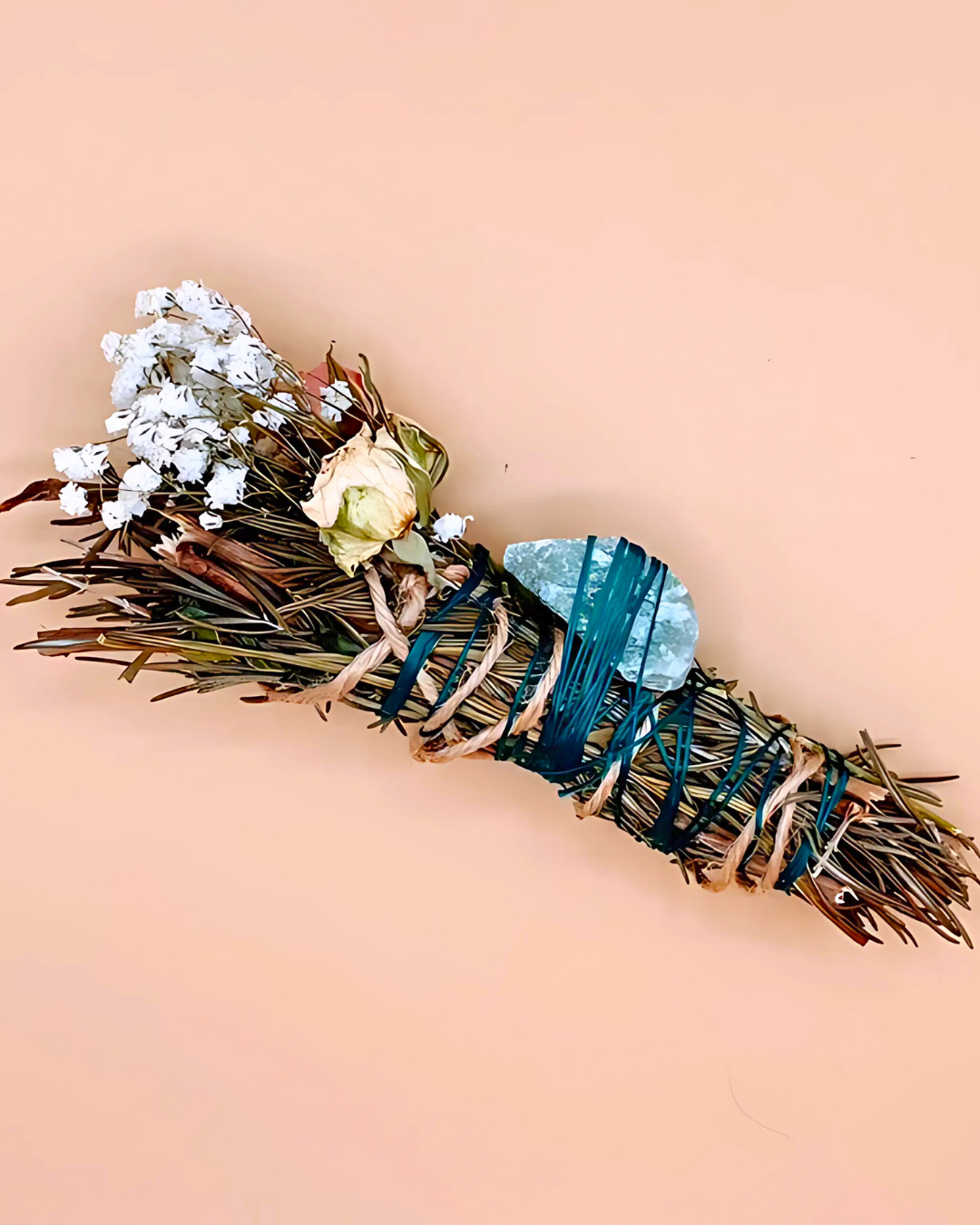 Sage bundle with flowers and stones on a peach background