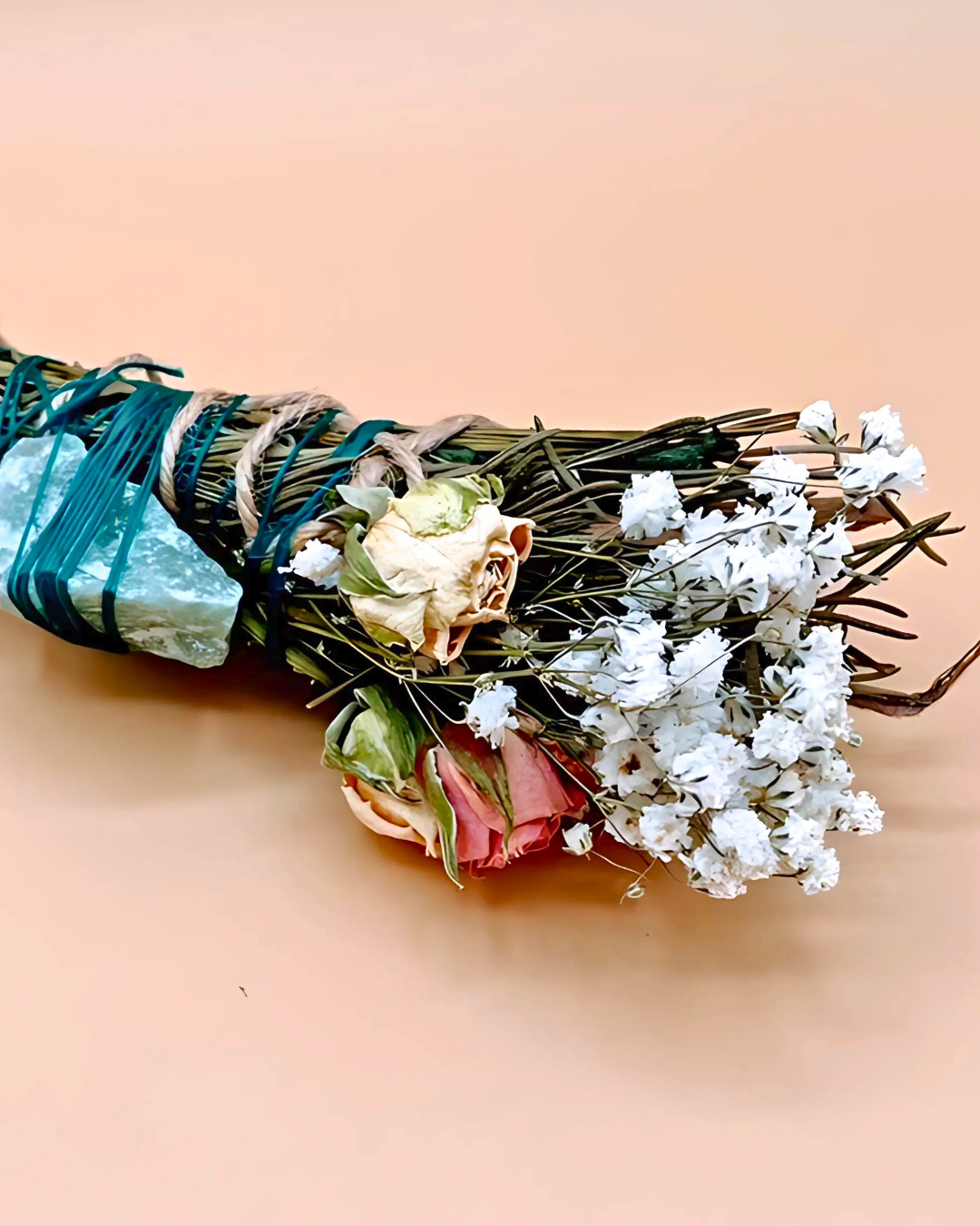 Bouquet of dried flowers and greenery tied with twine on a beige background