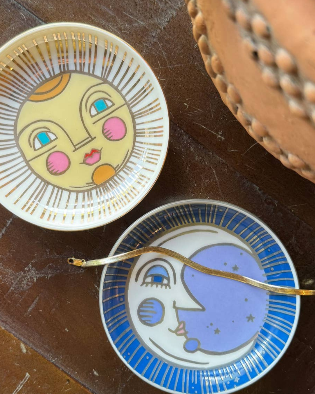 Two ceramic plates with artistic designs of a sun and moon on a textured surface.