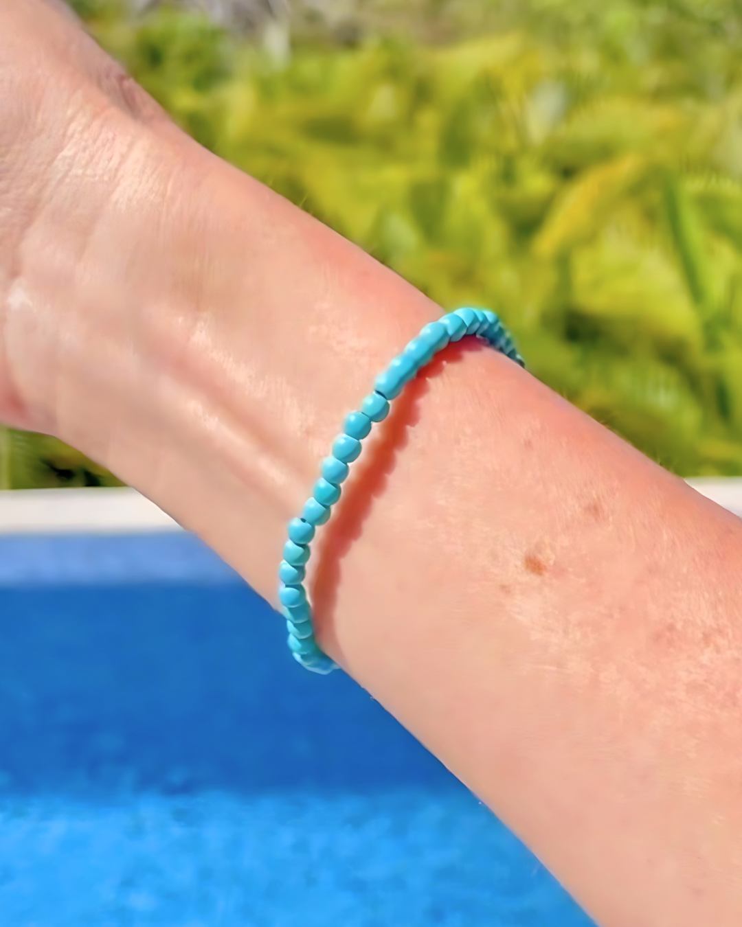 Turquoise beaded bracelet on a wrist with a blurred natural background