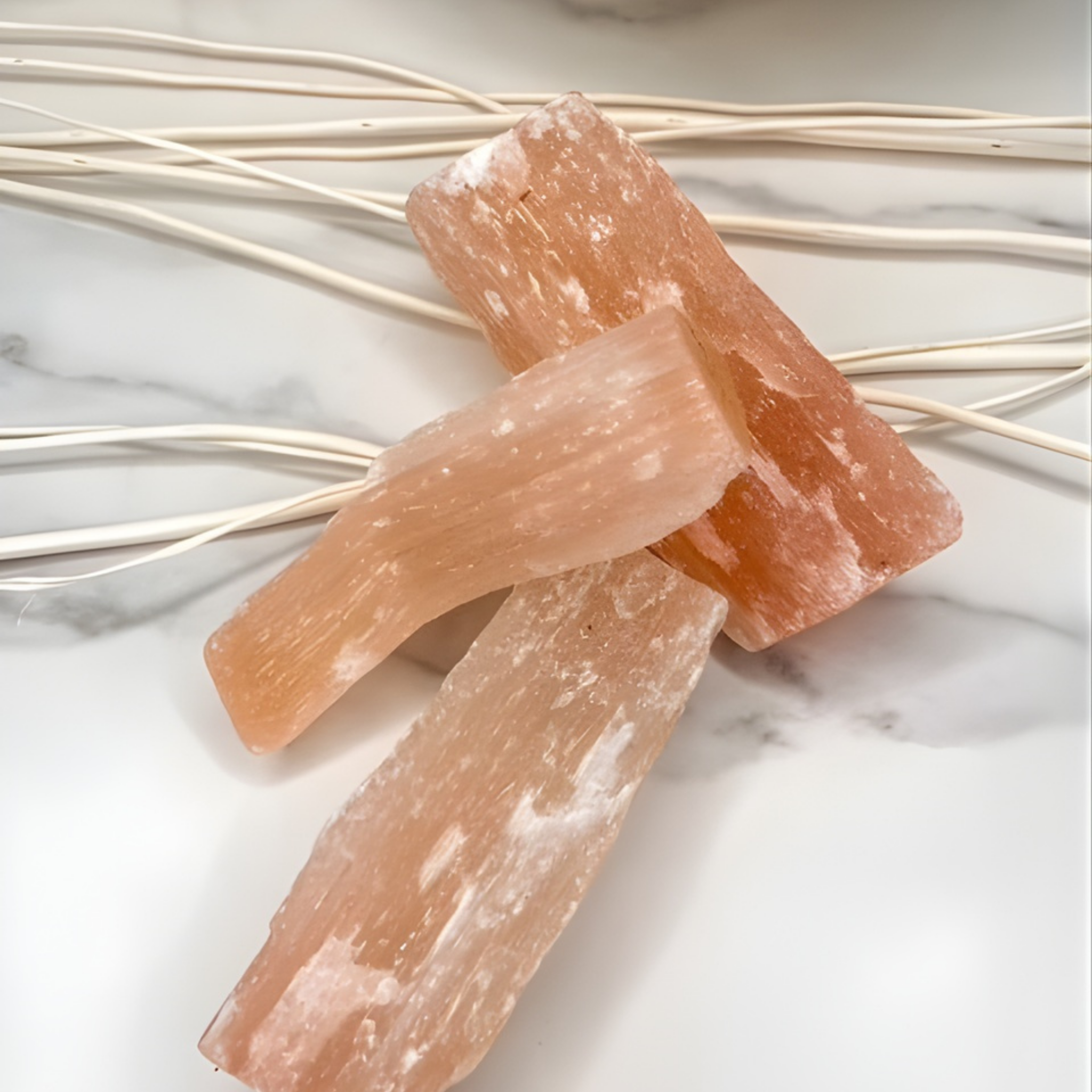 Two pink Himalayan salt blocks on a marble surface with gold decorative elements.