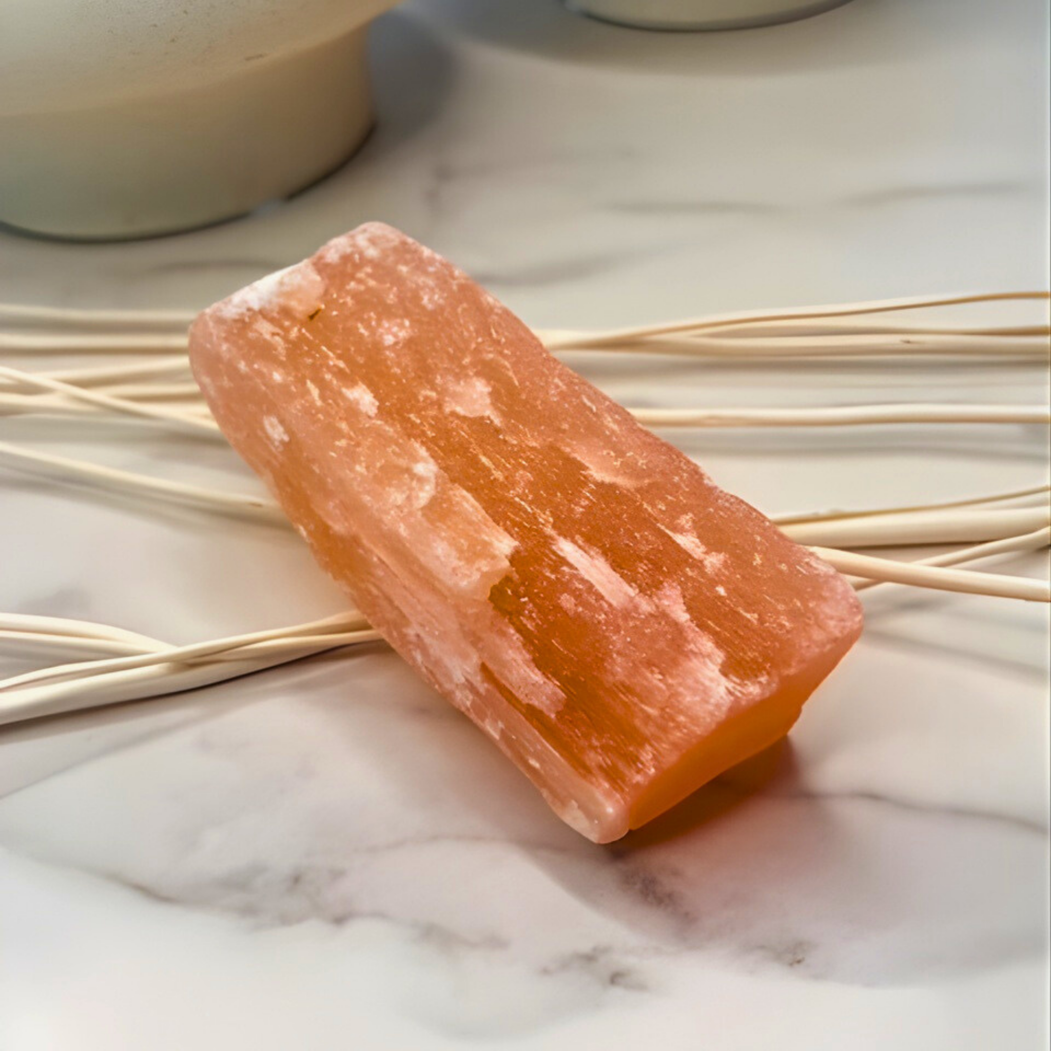 Rectangular pink soap bar on a marble surface with dried reeds