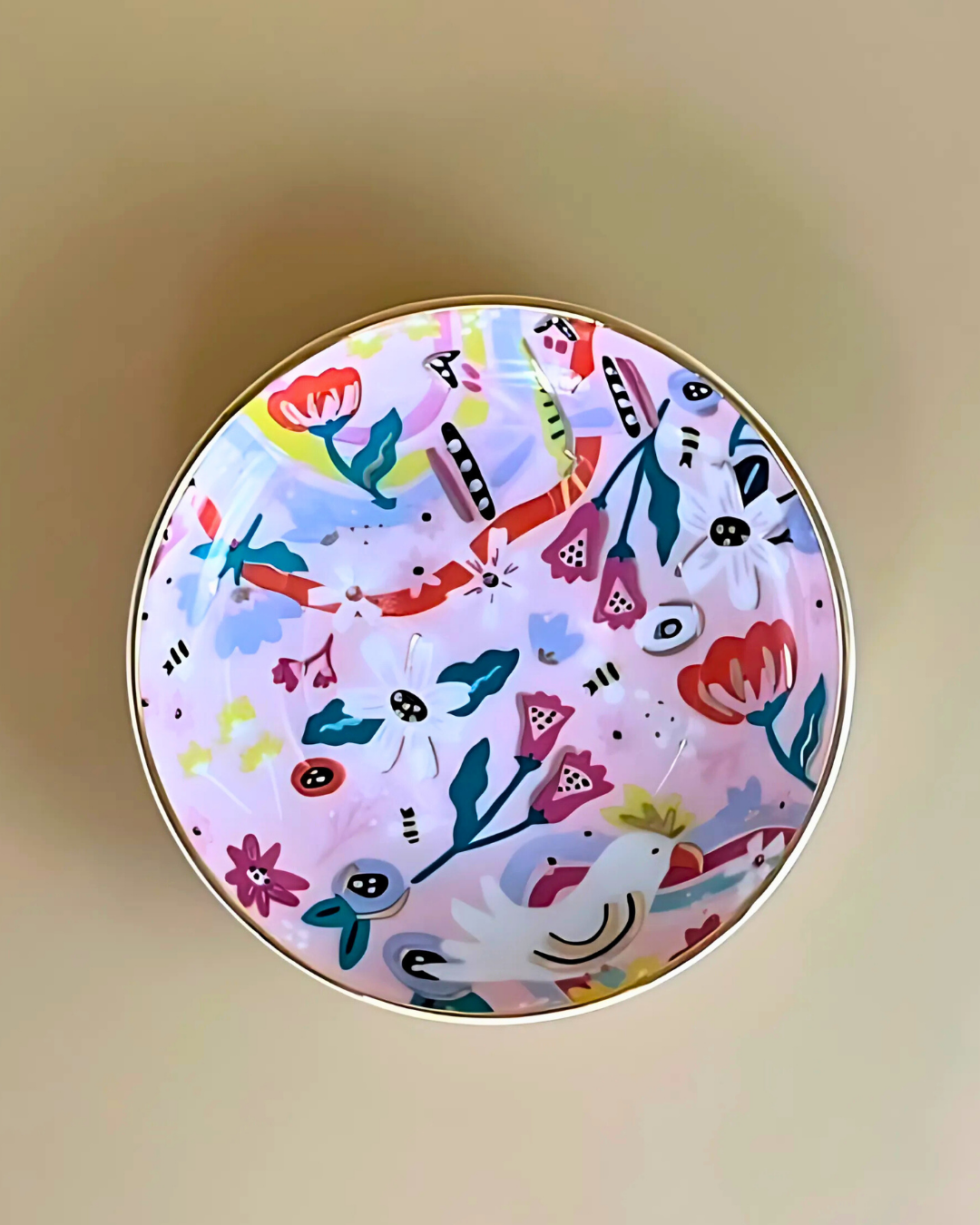 Round decorative item with colorful floral and animal pattern on a beige background
