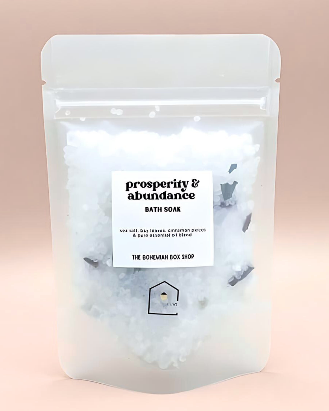 Bath soak package labeled 'Prosperity & Abundance' from The Bohemian Box Shop on a pink background