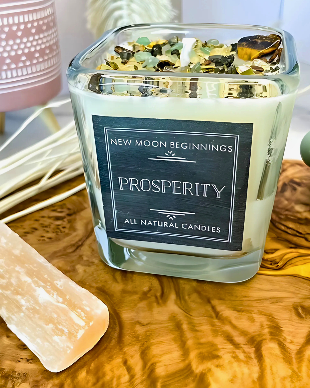 All natural candles labeled 'New Moon Beginnings Prosperity' on a wooden surface.