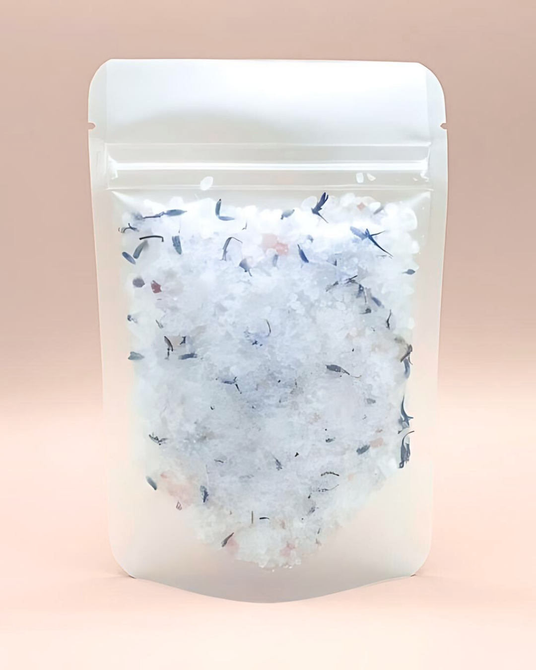 Packaged bath salts with visible herbs on a pink background