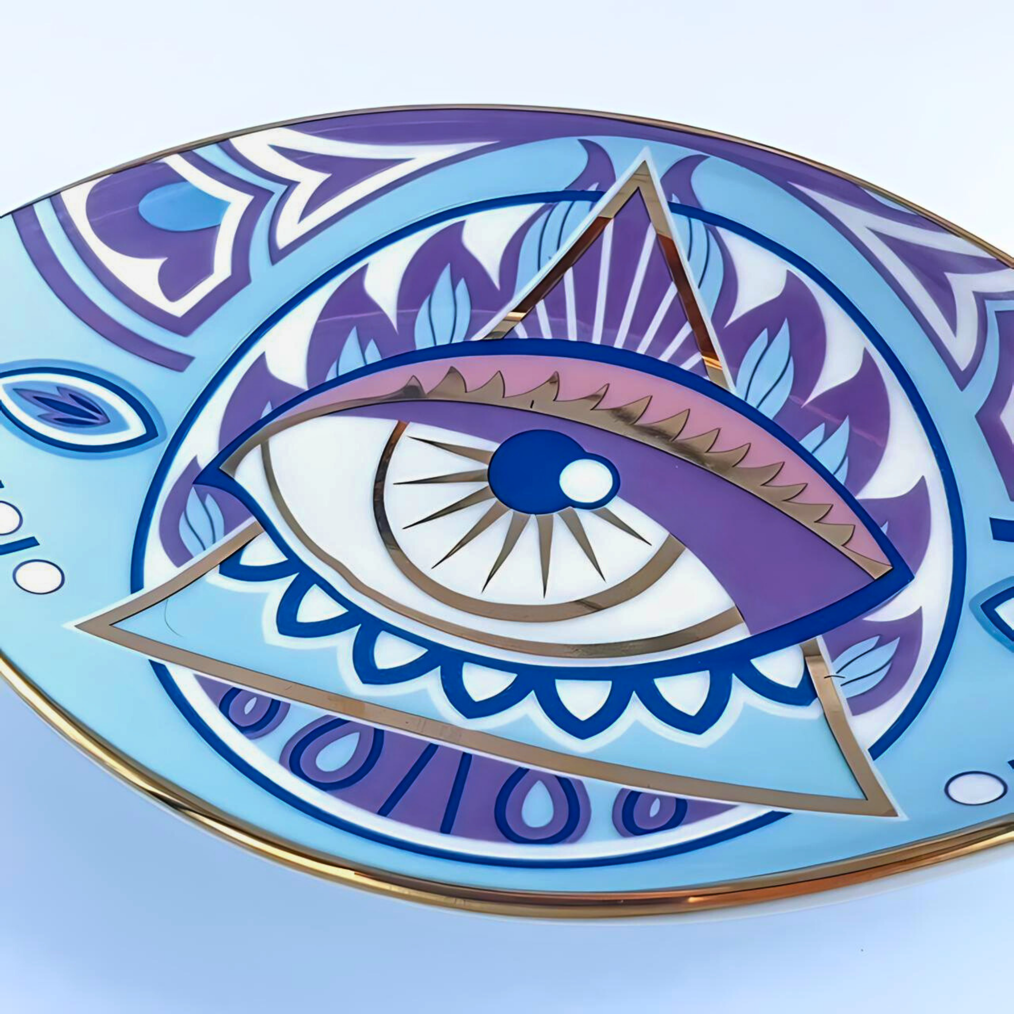 Decorative plate with eye and triangle design on a light blue background