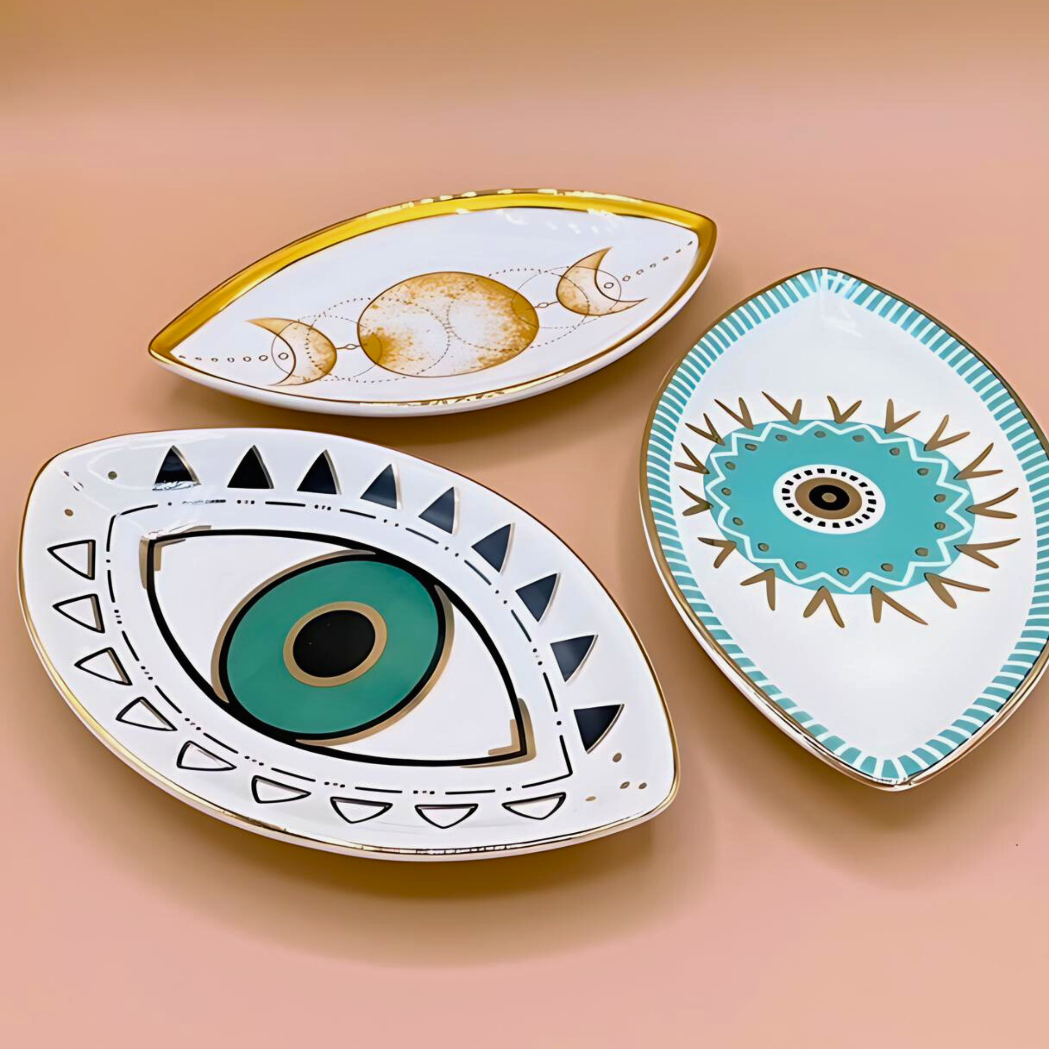 Three decorative plates with eye designs on a peach background