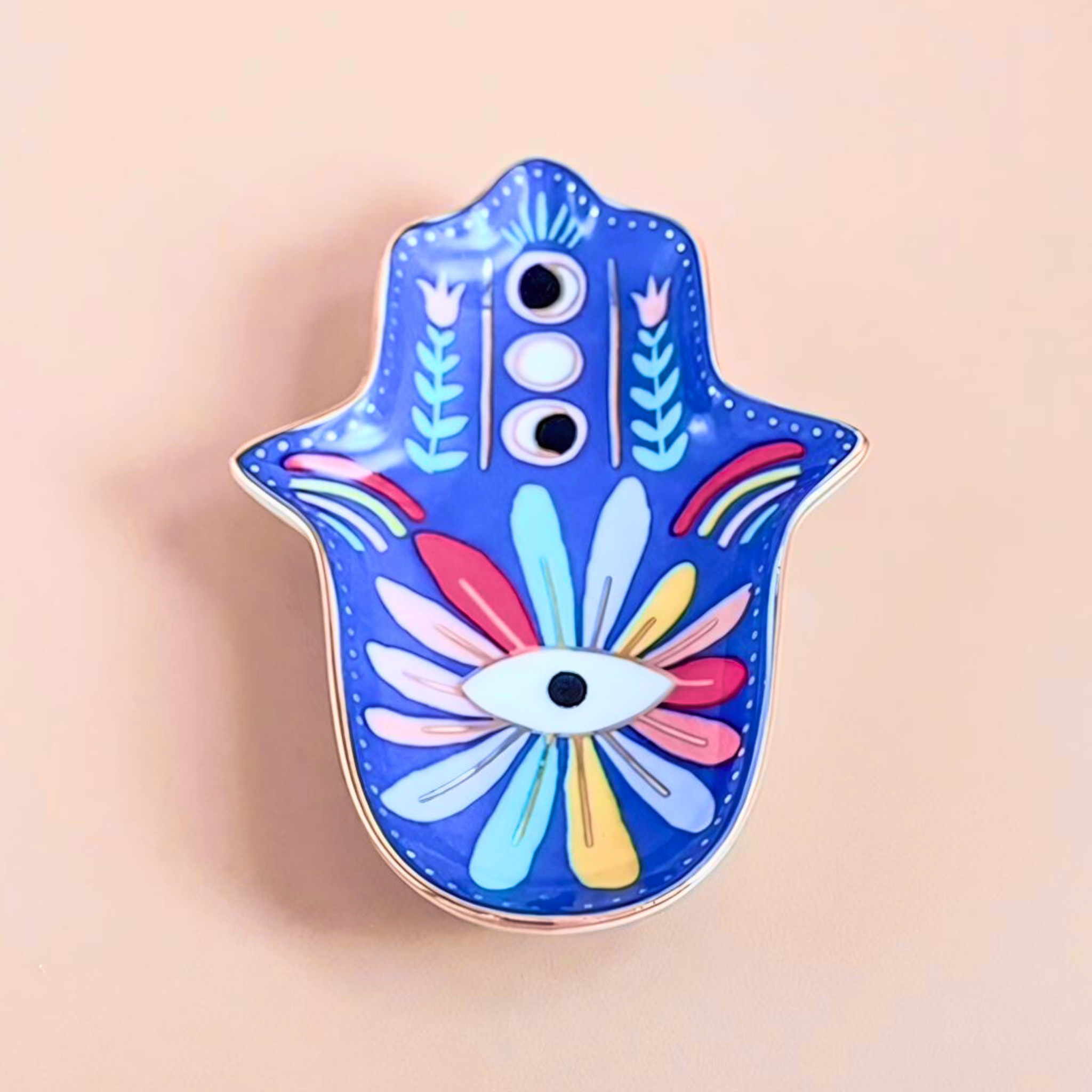 Colorful Hamsa hand pin with floral designs on a beige background