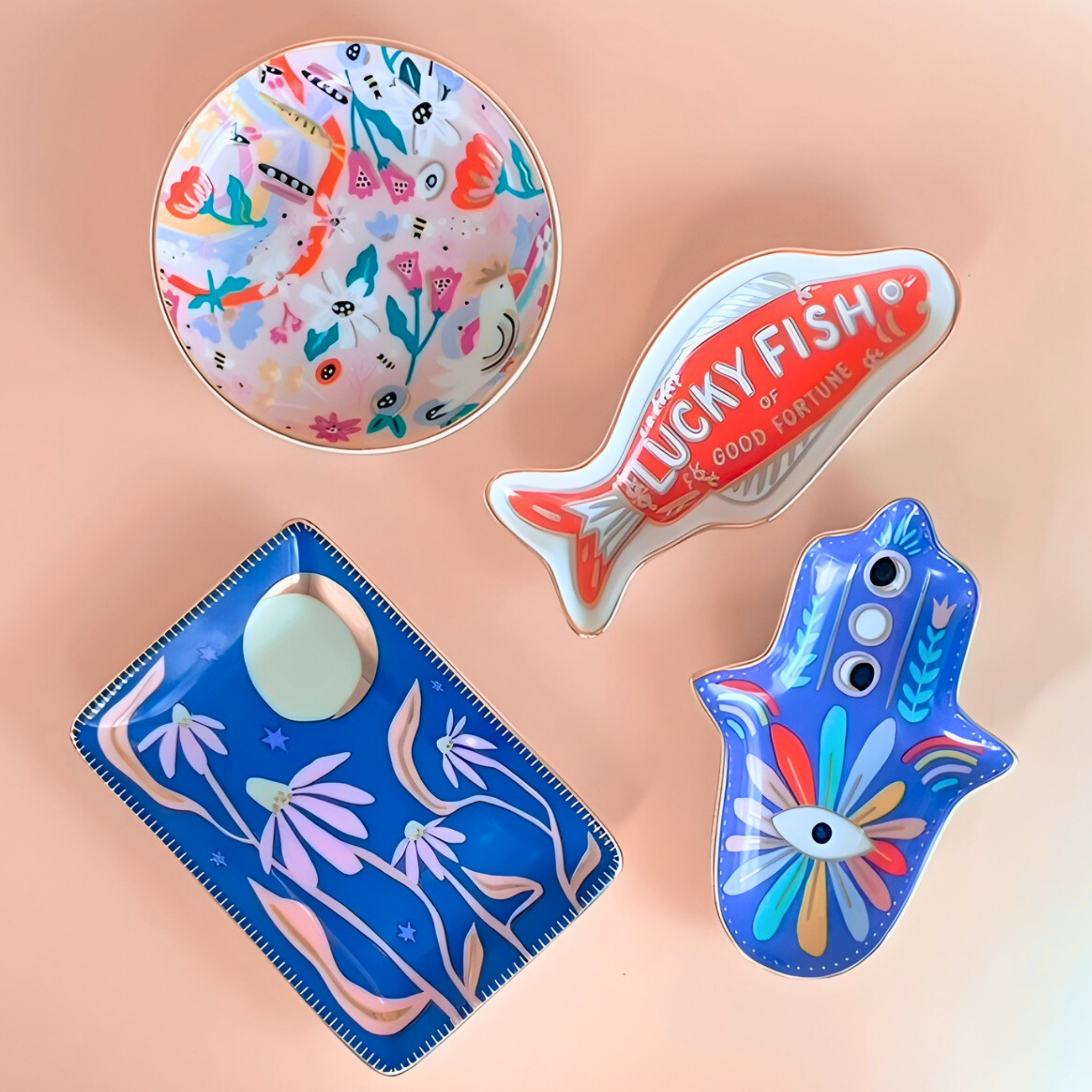 Collection of colorful decorative items including a fish-shaped object, a round plate with animal design, and a blue pouch with floral patterns on a peach background.