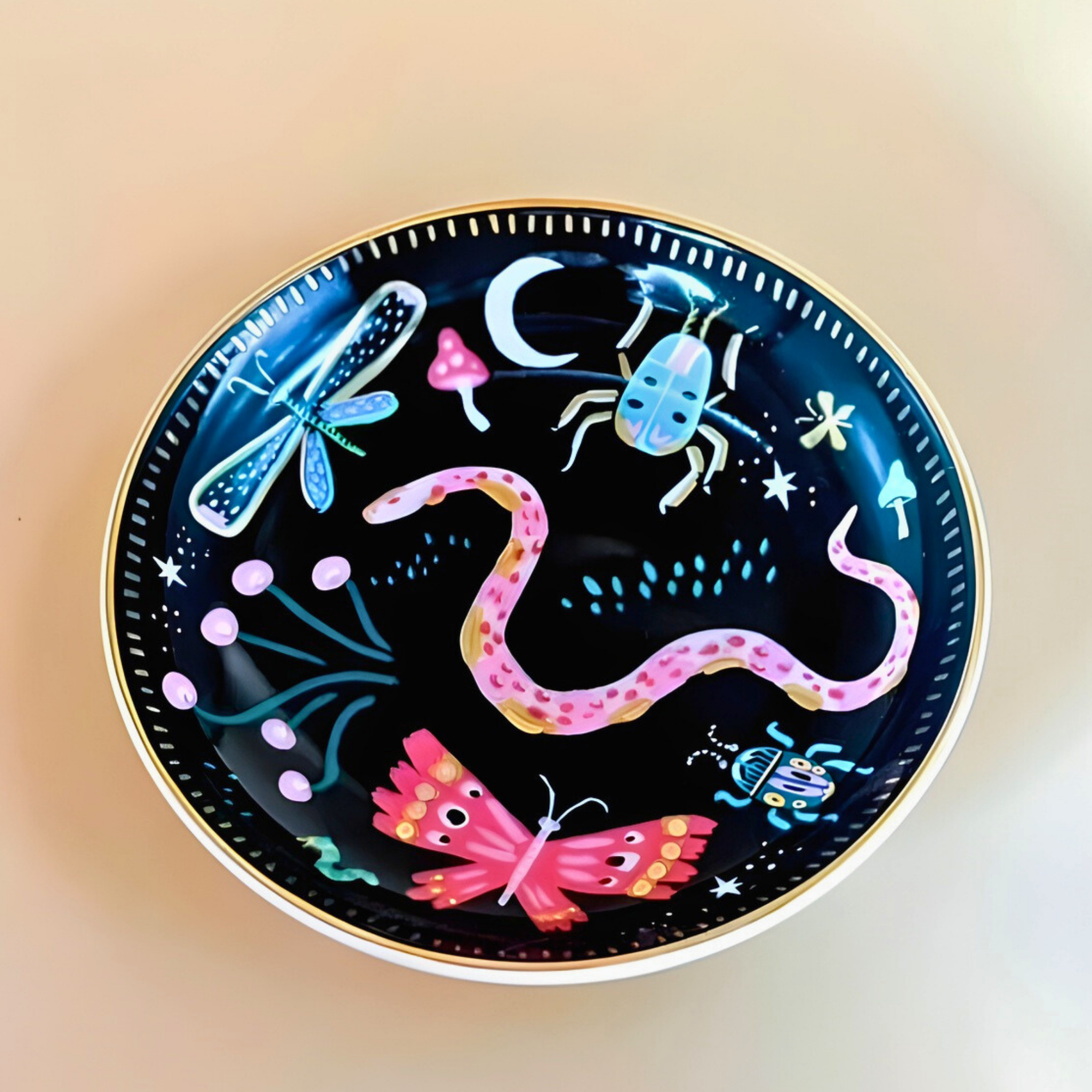 Decorative plate with colorful illustrations of a snake, butterfly, and other creatures on a black background.