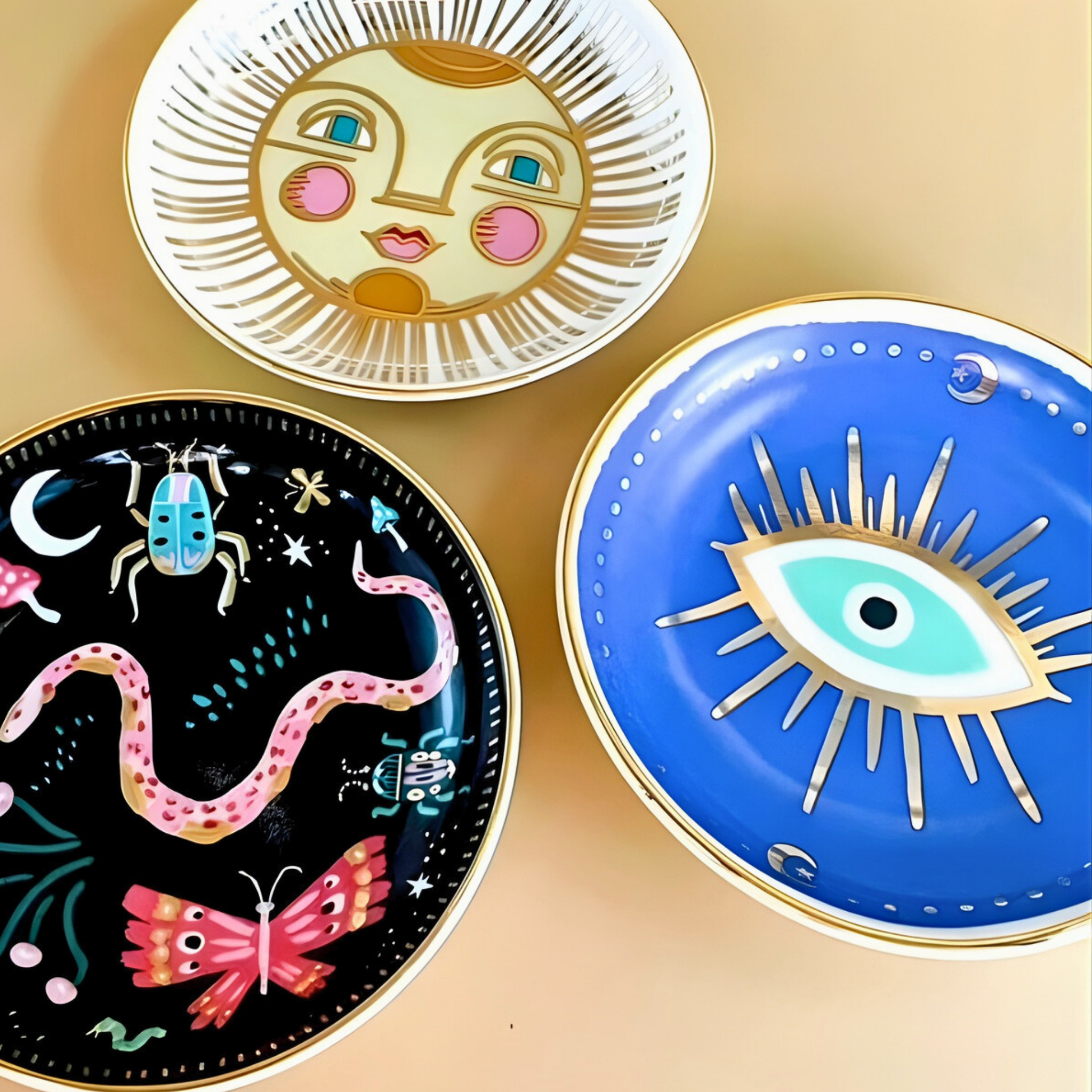 Three decorative plates with artistic designs on a beige background