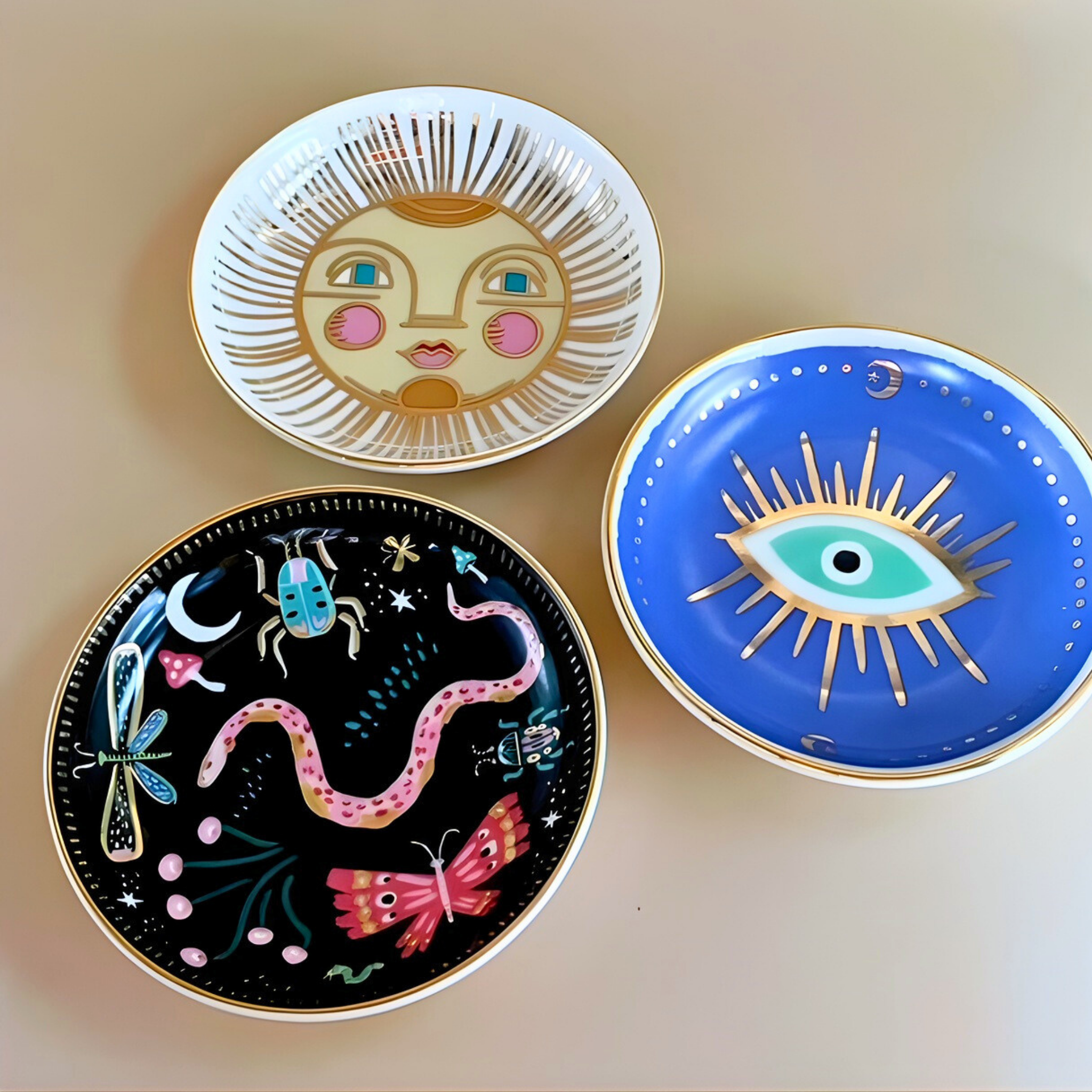 Three decorative plates with artistic designs on a beige background