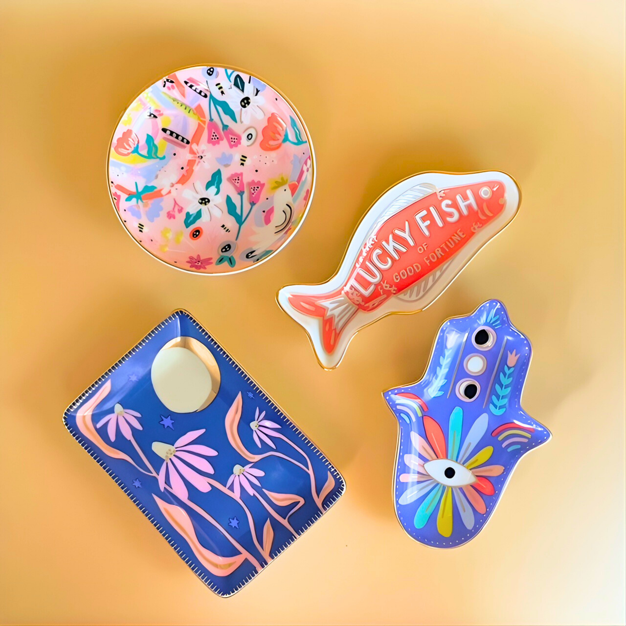 Colorful ritual ring dish including a fish-shaped magnet, a plate with floral design, and two other toys on a yellow background.