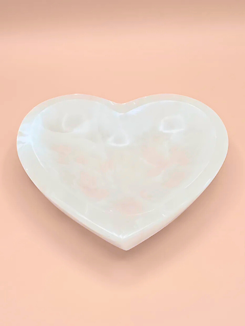 Heart-shaped white stone on a pink background