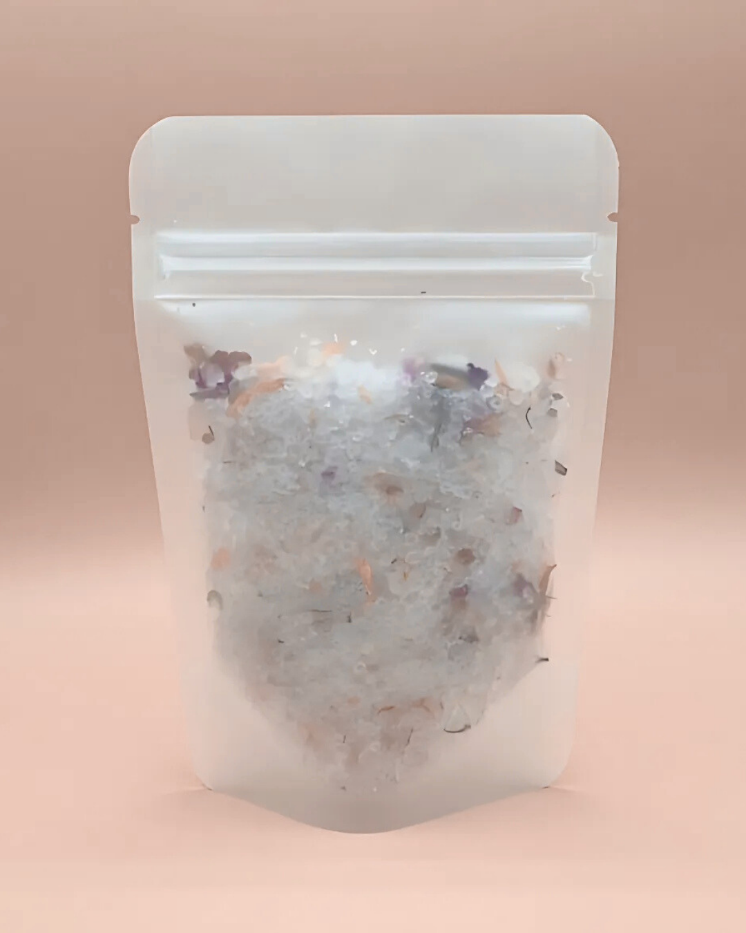 Clear packaging bag with a bath salt mix on a pink background