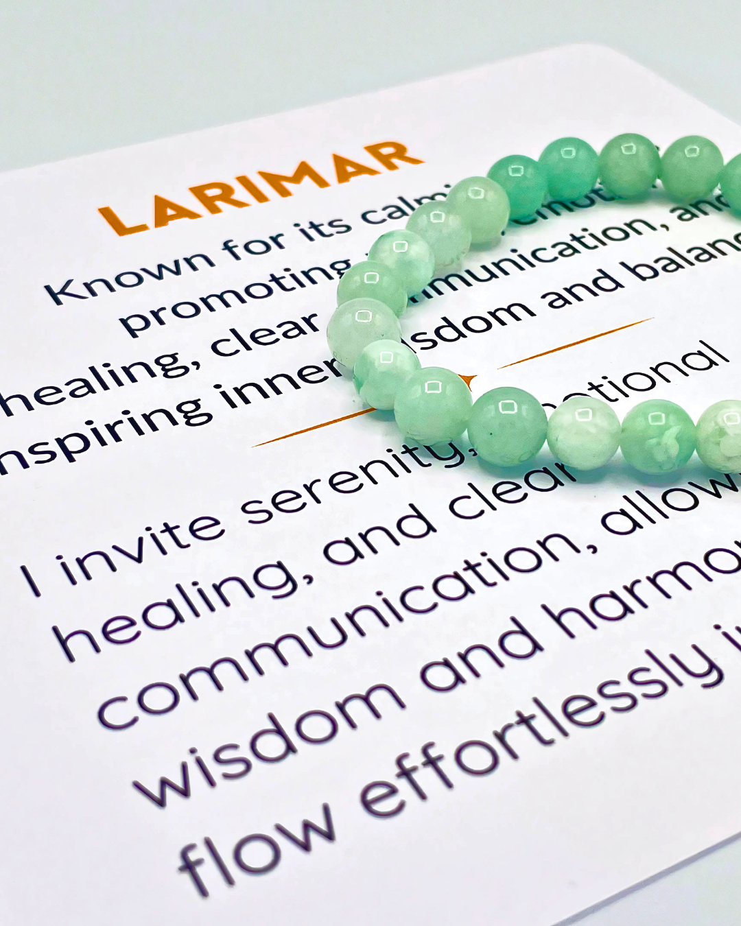 Green beaded bracelet on a piece of paper with text about Larimar