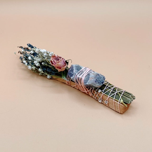 Decorative bundle with flowers, stones, and twine on a beige background