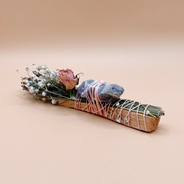 Smudge stick with flowers and stones on a beige background