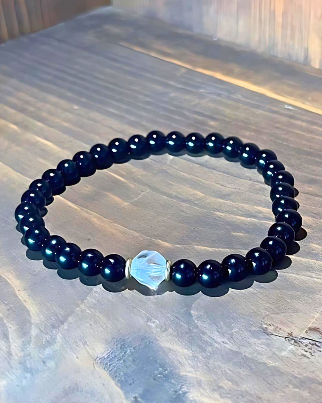 Navy blue beaded bracelet with a silver hexagonal charm on a marble surface