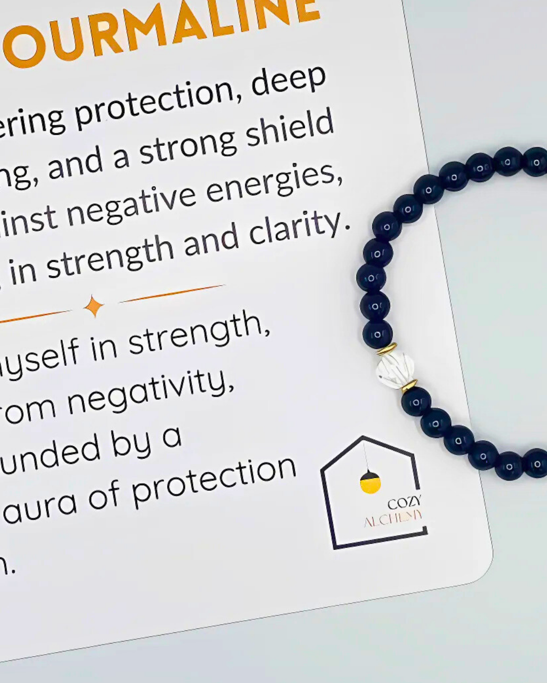 Navy blue beaded bracelet with a white charm on a Cozy Alchemy branded card.