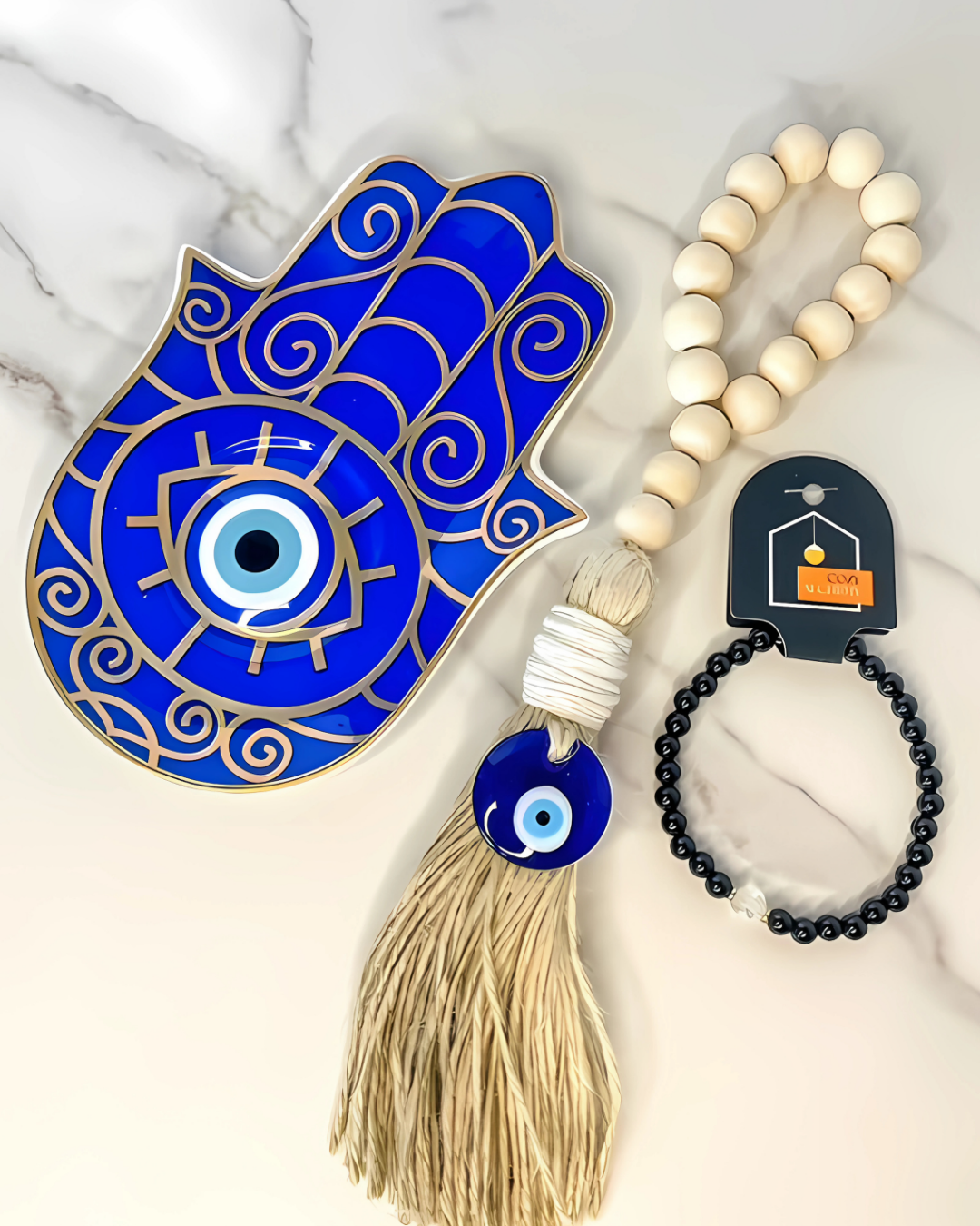 Blue Hamsa hand with tassel, evil eye bead, and black beaded bracelet on marble surface
