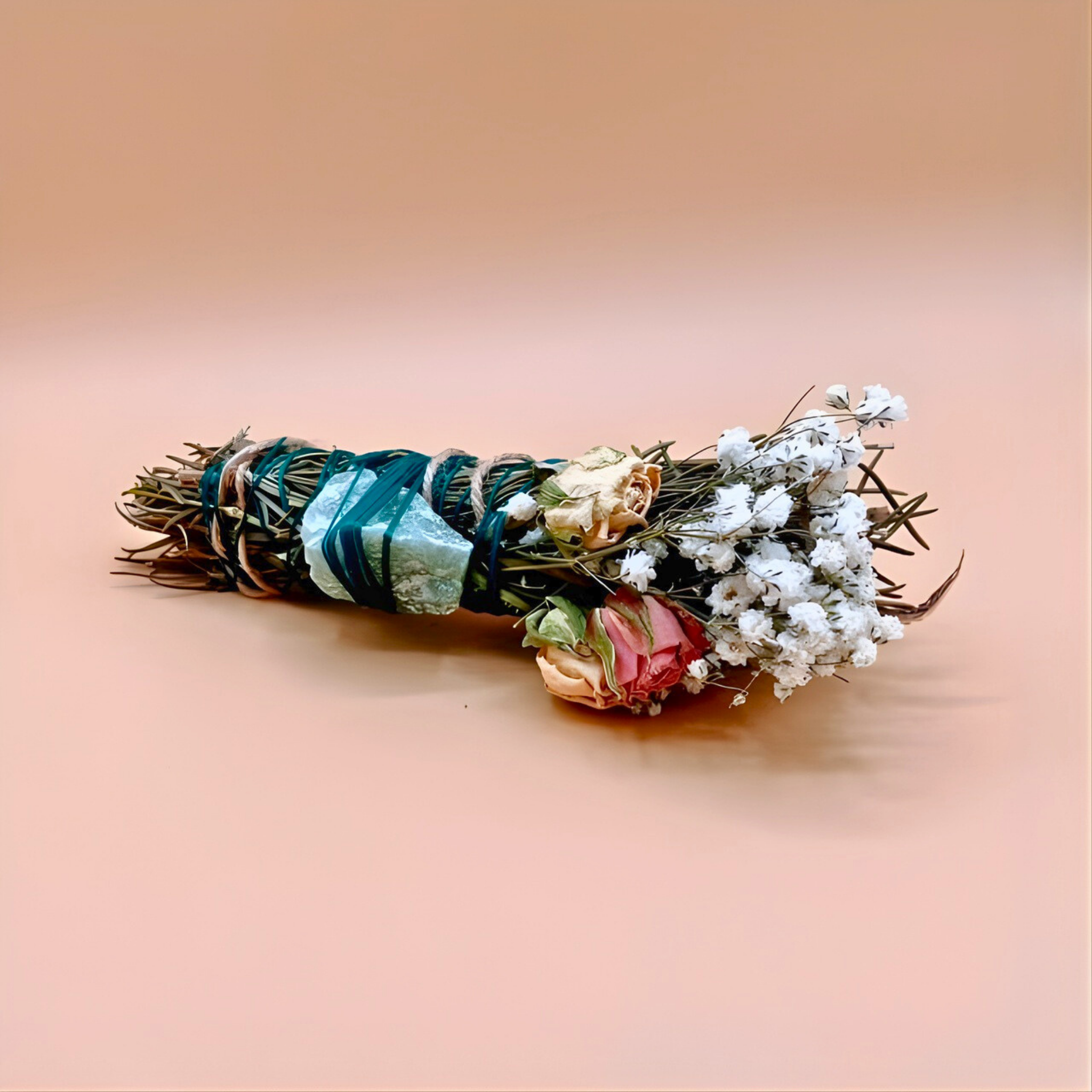 Sage smudge stick with flowers and stones on a beige background