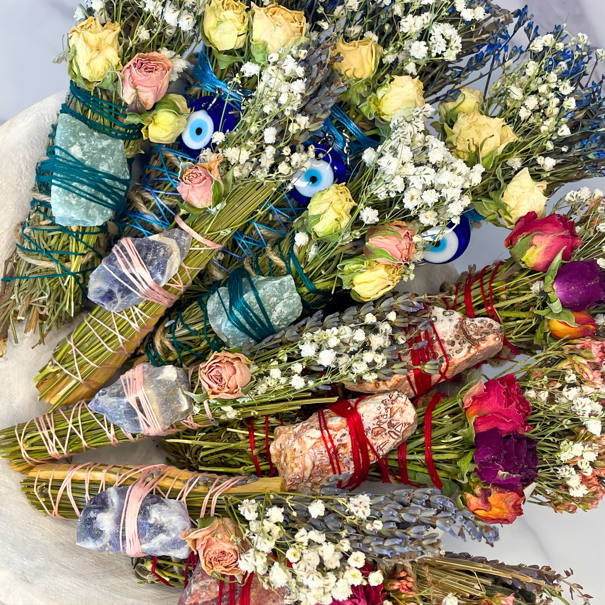 Collection of dried flowers, herbs, and crystal bundles on a white surface
