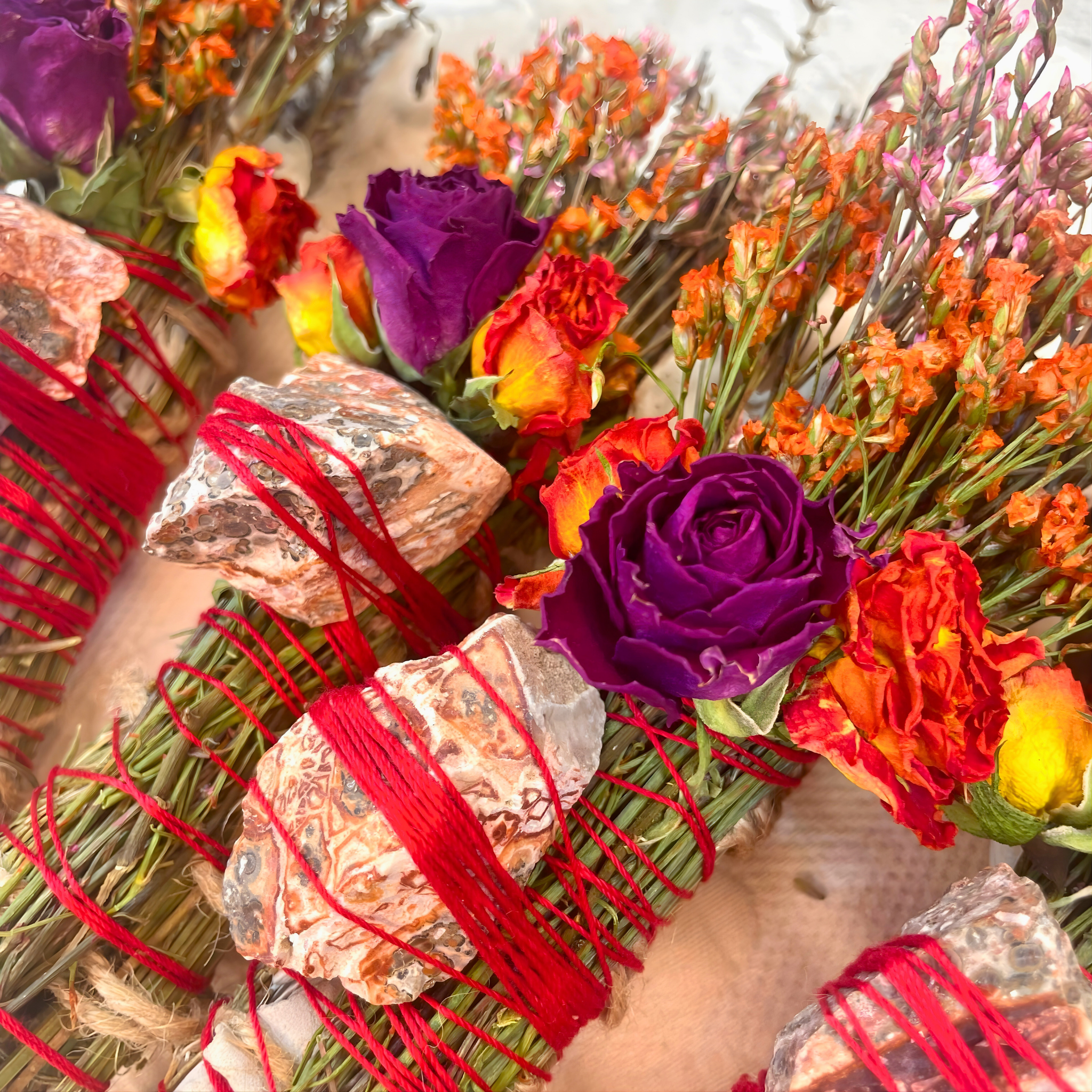 Bouquet of colorful flowers with red ribbons and stones on a textured surface