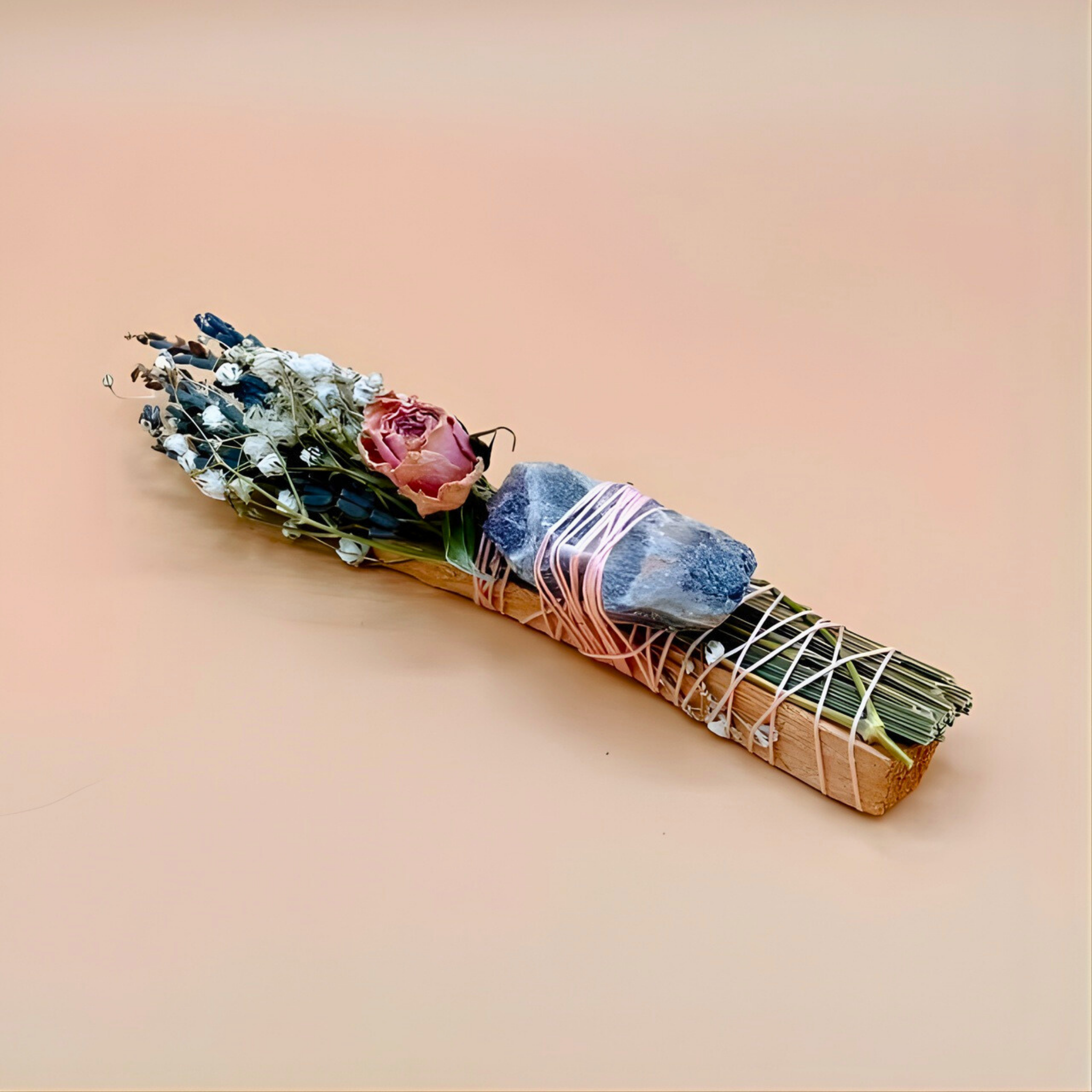 Decorative bundle with flowers, stones, and twine on a beige background