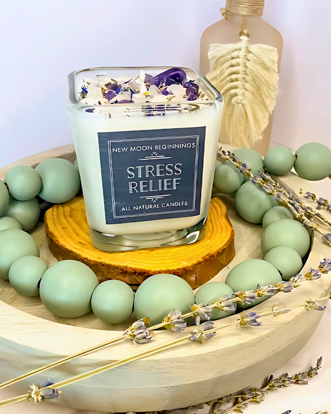 Candle labeled 'Stress Relief' on a decorative stand with green beads and lavender flowers.