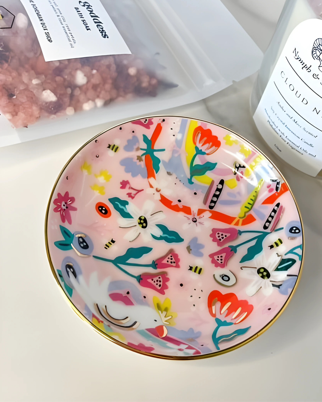 Decorative plate with colorful floral and insect design on a white surface with other products.