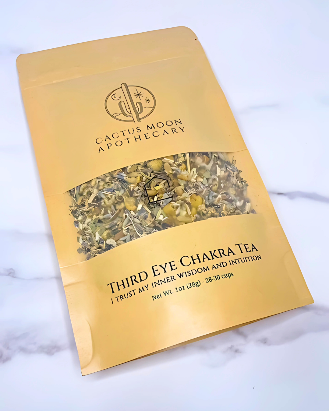 Gold packaging of Cactus Moon Apothecary Third Eye Chakra Tea on a marble surface
