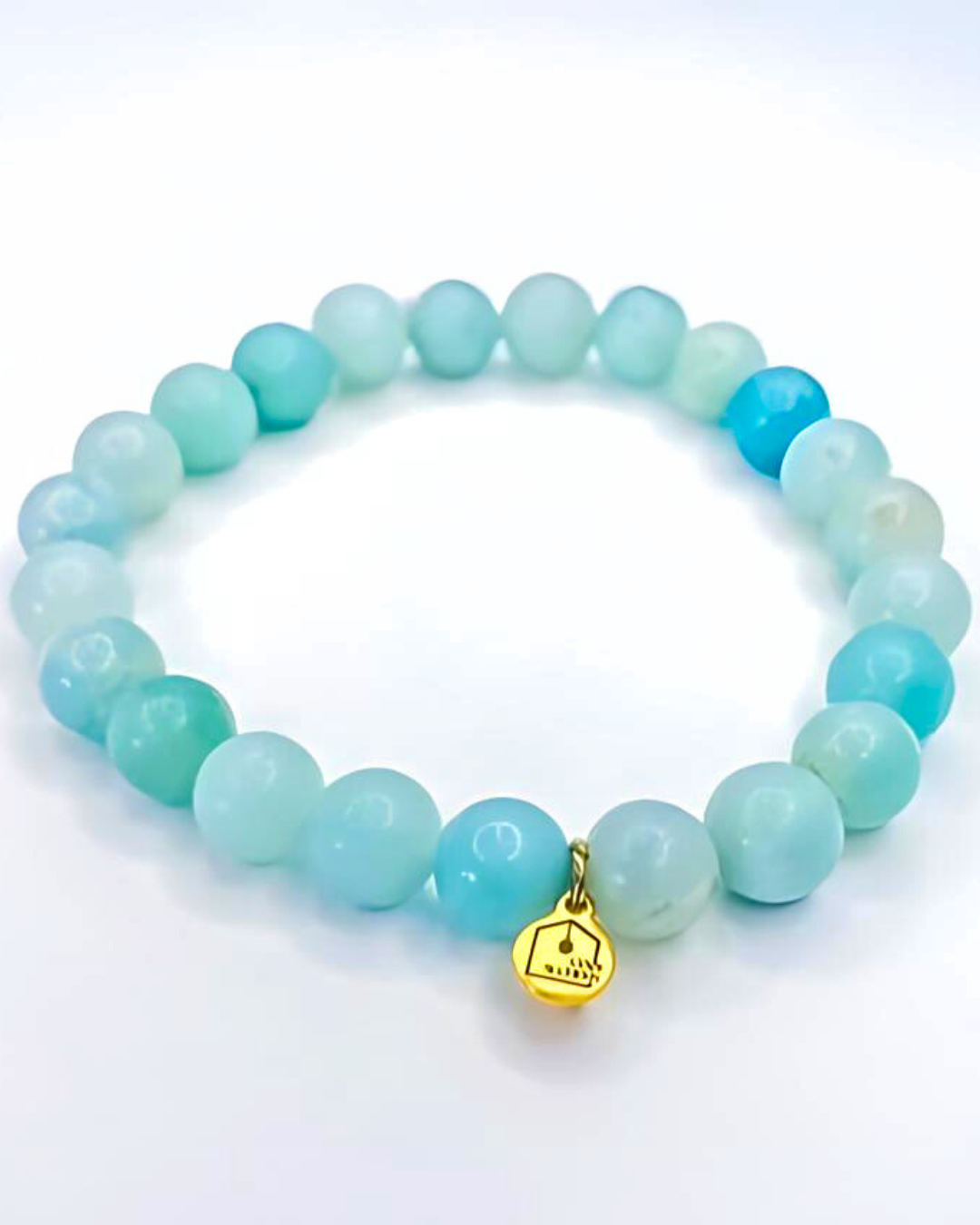 Turquoise beaded bracelet with a gold charm on a white background