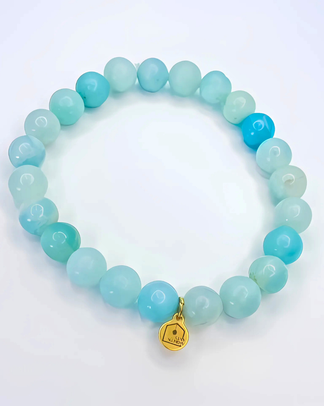 Turquoise beaded bracelet with a gold tag on a white background