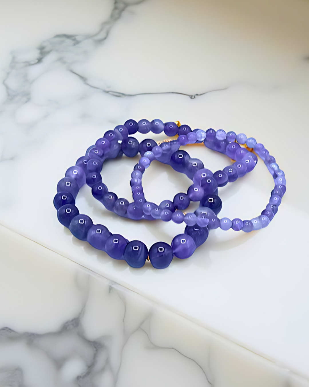 Set of purple beaded bracelets on a marble surface