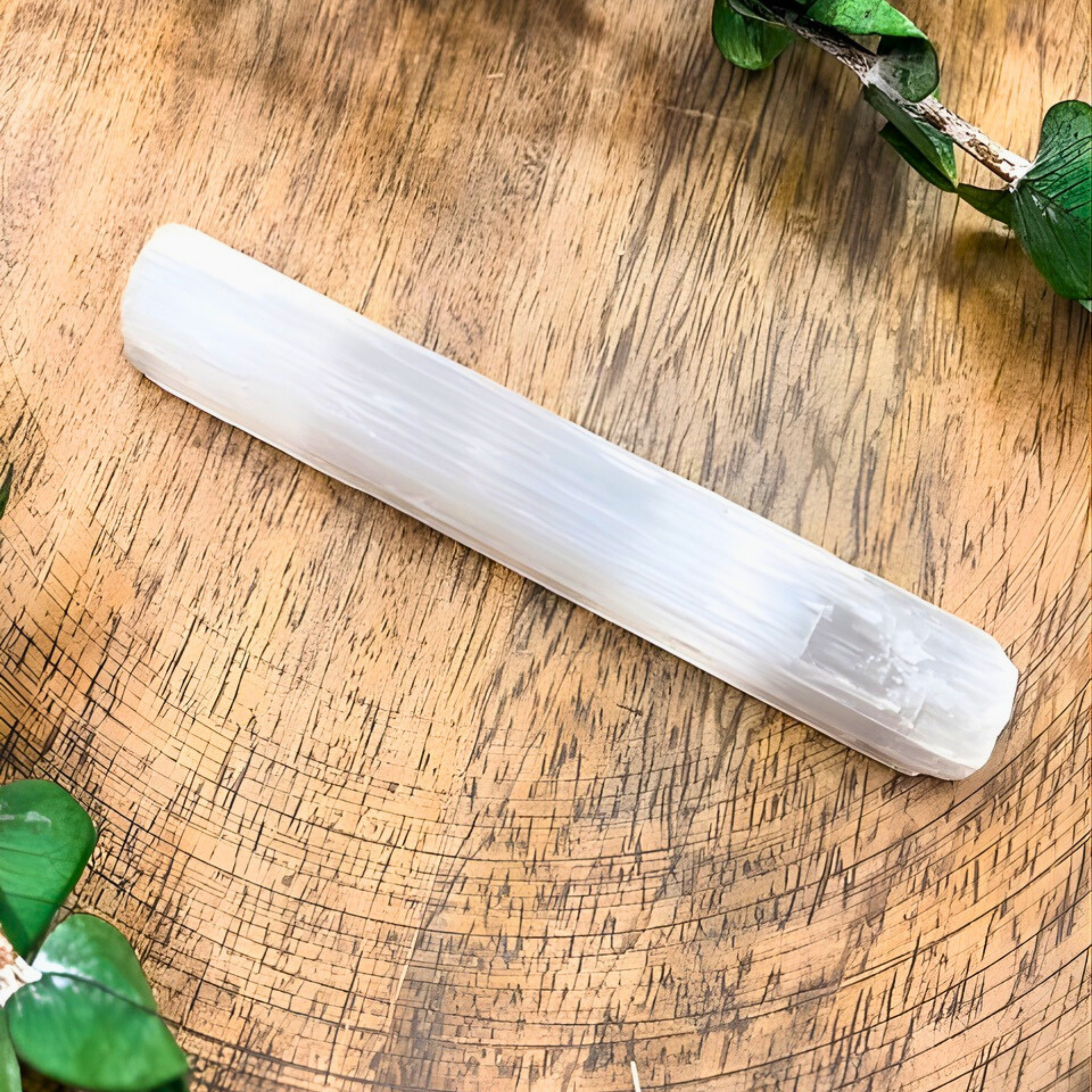 Crystal wand on a wooden surface with green leaves