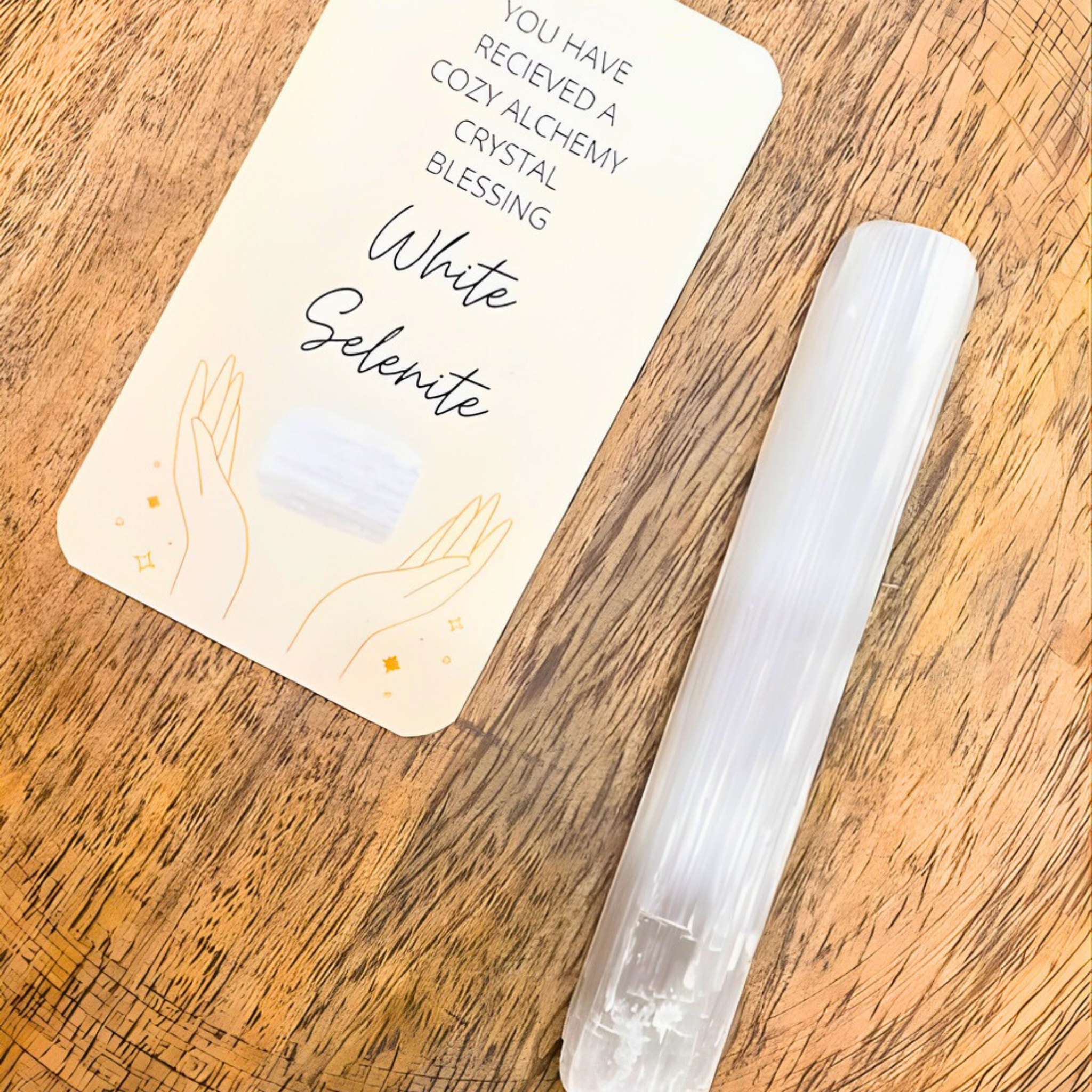 White selenite crystal on a wooden surface with a blessing card.