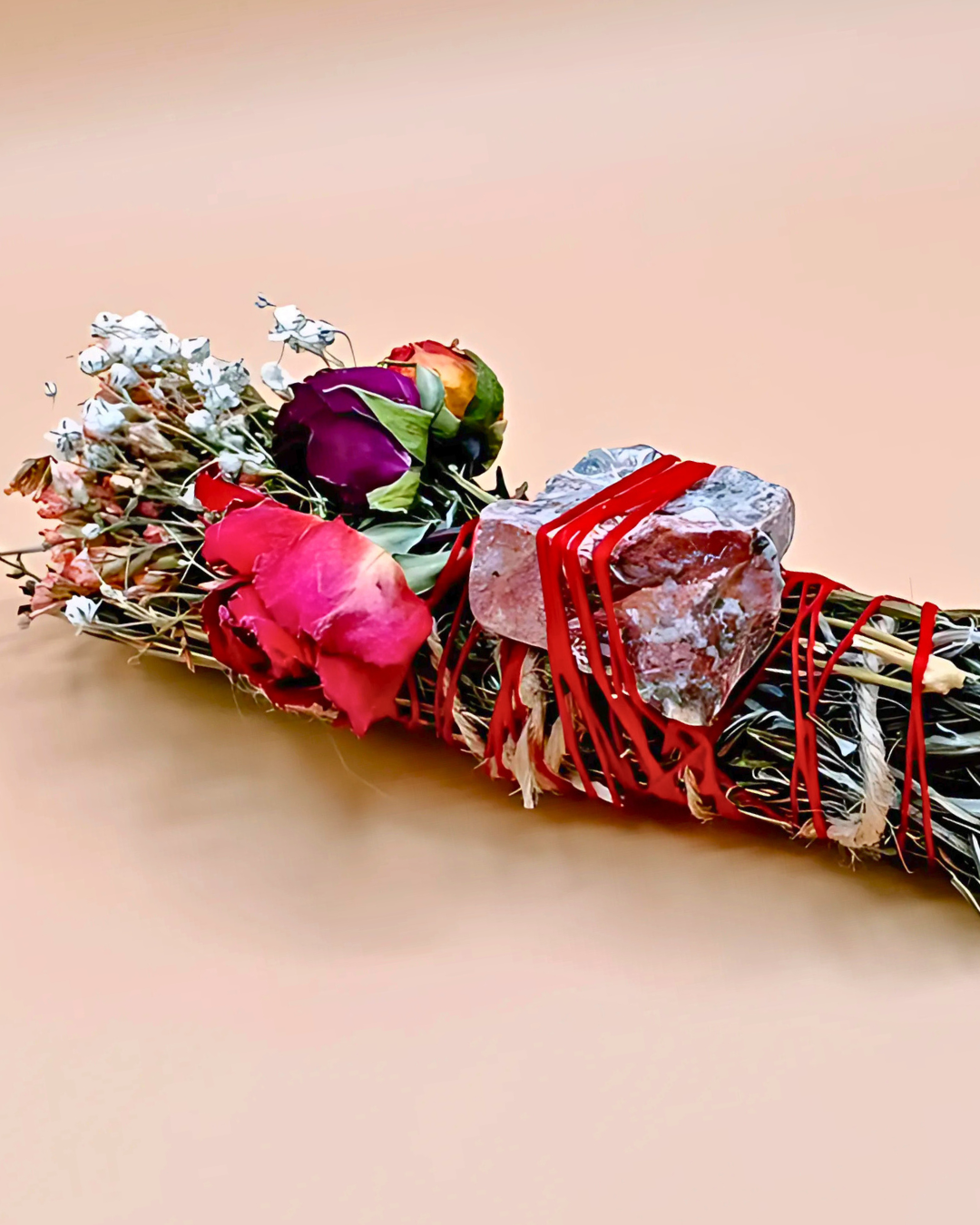 Bouquet of dried flowers and herbs tied with red string on a beige background