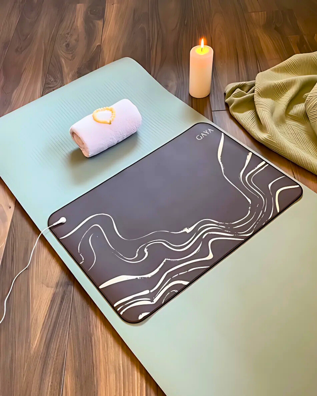 Yoga mat with a mouse pad on a wooden floor, featuring a candle and towel.