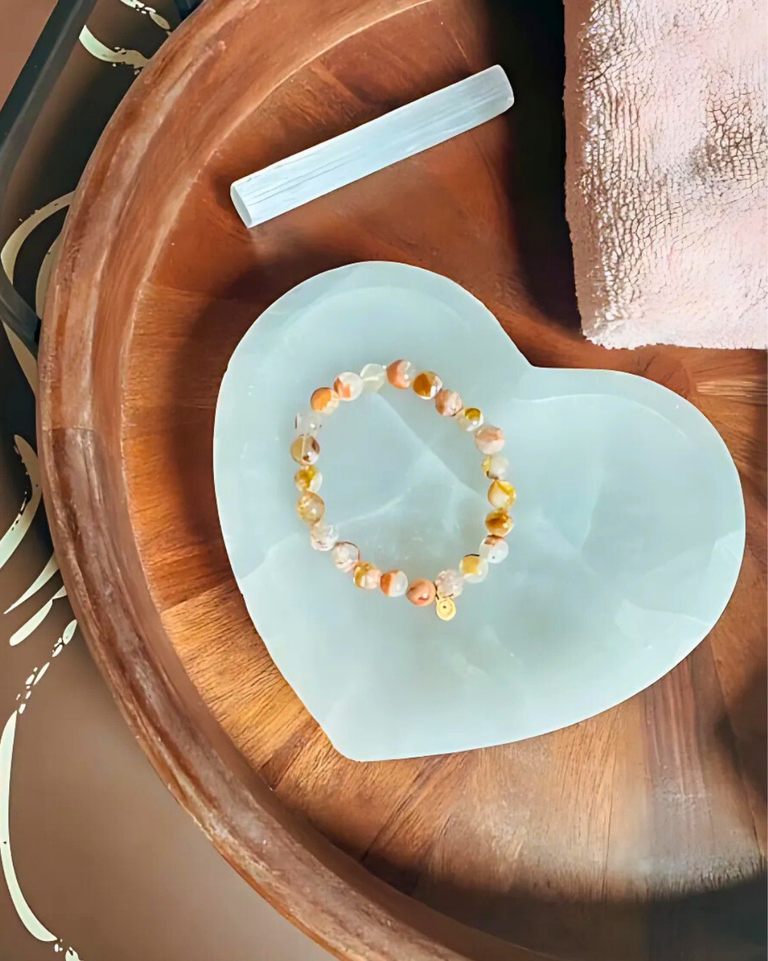 Beaded bracelet on a heart-shaped light blue stone with a wooden tray in the background