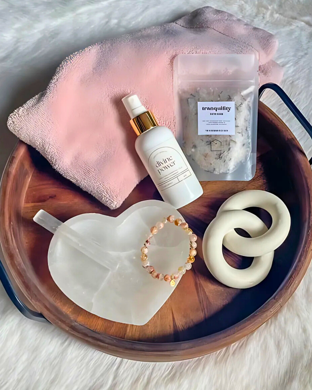 Wooden tray with skincare products, a towel, and decorative items on a light background