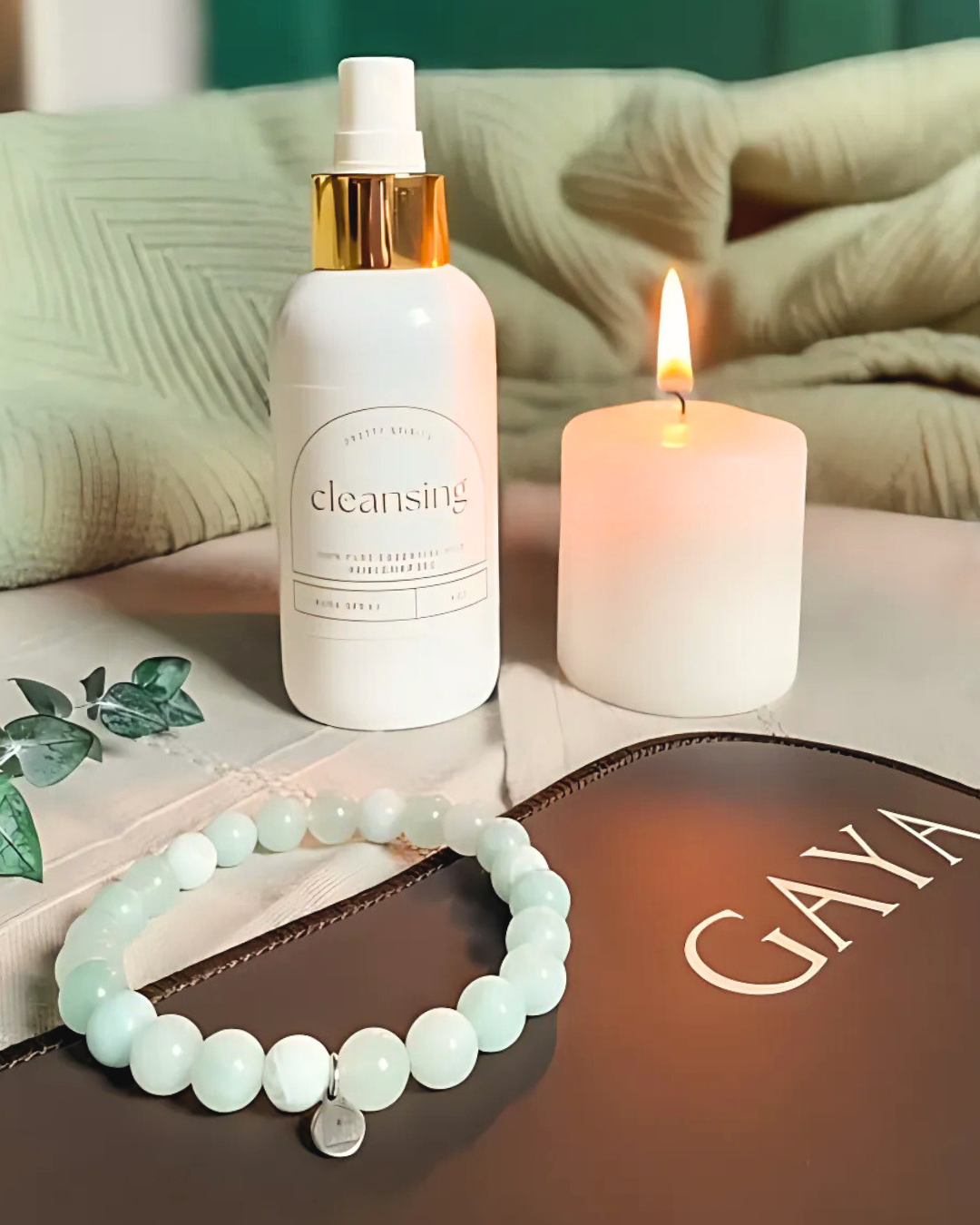 Cleansing bottle, candle, and bracelet on a surface with 'GAYA' branding.