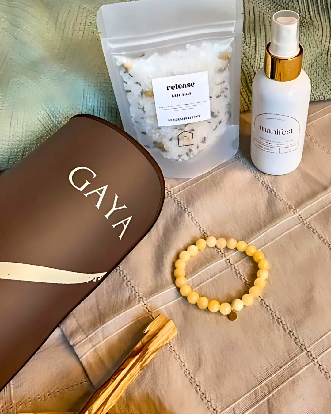 Gaya product,Manifest bottle, and bracelet on a textured surface