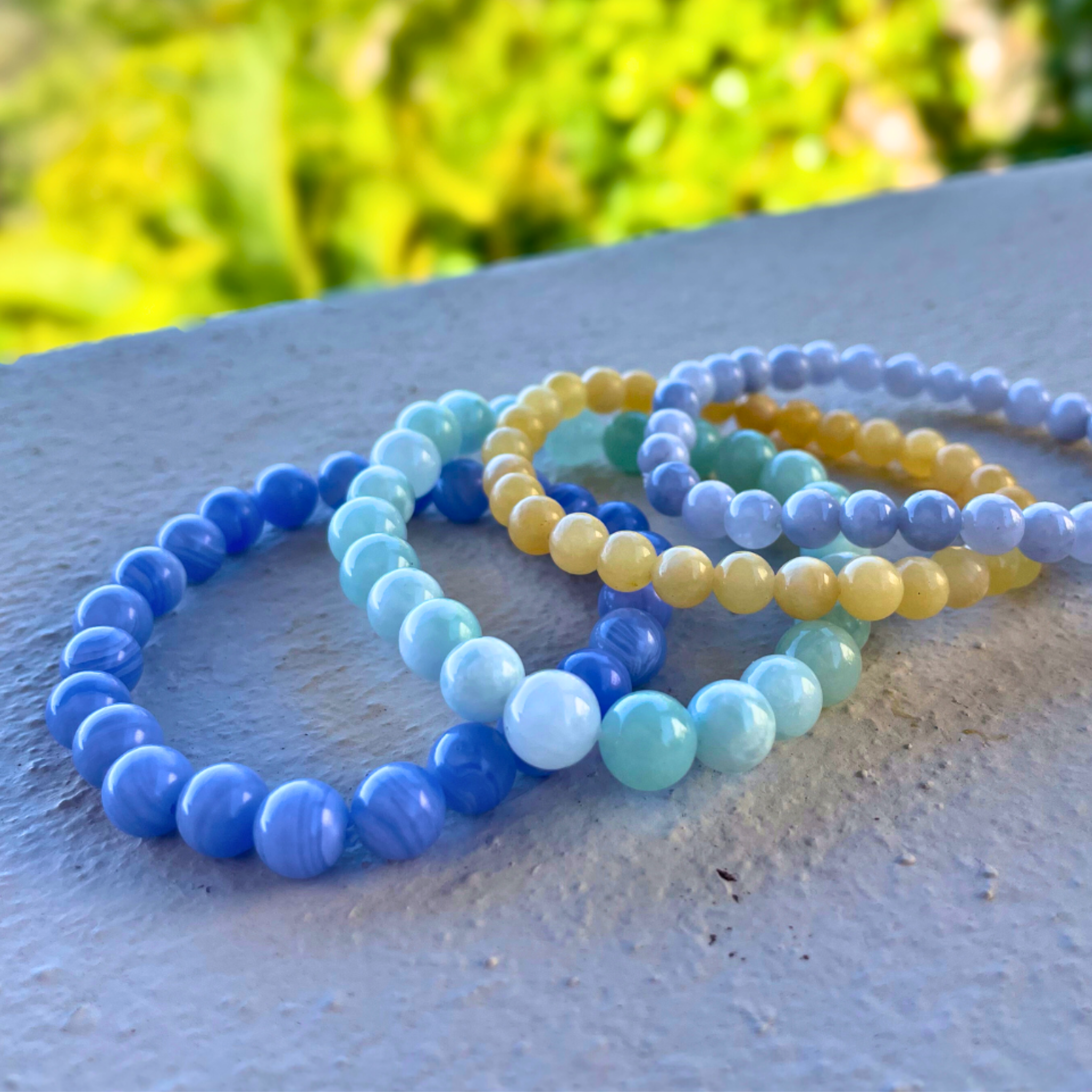 Set of colorful beaded bracelets on a textured surface with a blurred green background
